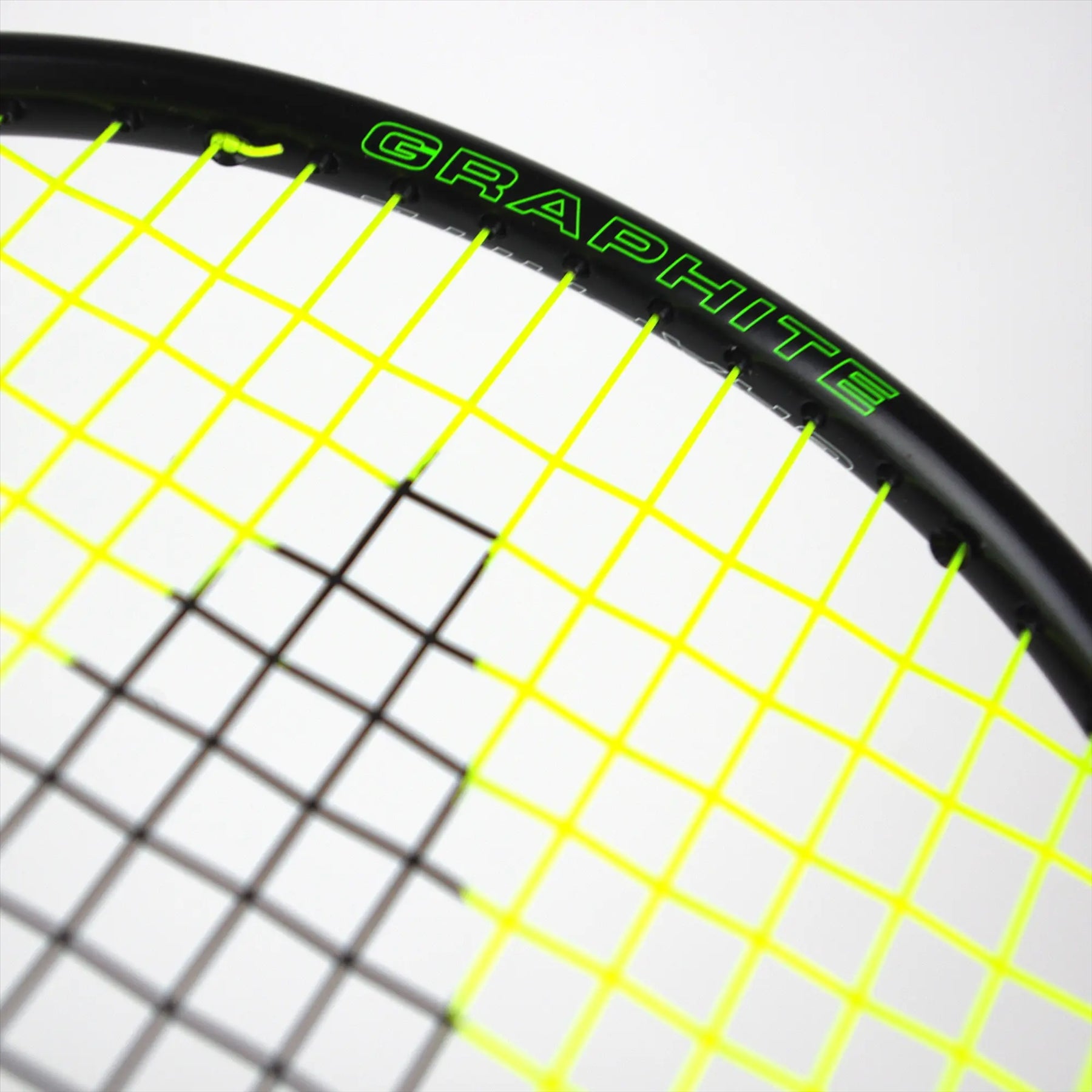 Close-up of a badminton racket, the Karakal BZ 20 2.1, showcasing its isometric head and top section of the frame and strings. The sleek black frame displays "Karakal" in green, while vibrant yellow strings provide a pop of color. A PU Super Grip ensures comfort and control for every swing.