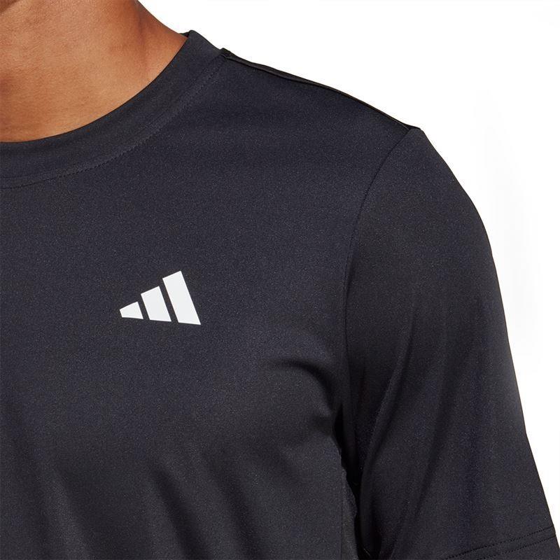 A person is wearing a black ADIDAS Men's Club Badminton T-shirt featuring a white geometric logo with three diagonal stripes on the chest. The background is plain white.