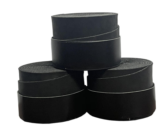 Four rolls from a 3-pack of Badminton HQ's black overgrip tapes are arranged with precision, much like stacked badminton overgrips. Two rolls rest at the base, side by side, with two more on top, creating a pyramidal shape. The glossy overgrips are tightly wound, promising excellent comfort and performance.