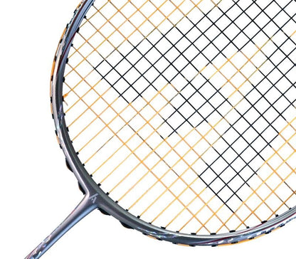 Close-up of an Ashaway Phantom Shard 3 3U Badminton Racket in Orange, showcasing its head with Zymax 68TX strings forming a colorful geometric grid. The metallic frame shows wear from frequent play, enhanced by Shardtech technology for durability.