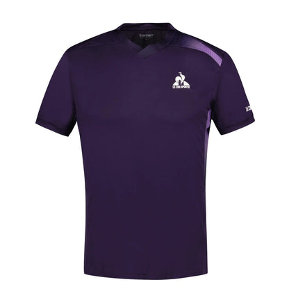 The Le Coq Sportif Pro Men's Badminton T-Shirt in Deep Purple boasts a V-neck and short sleeves. Designed with breathable polyester material, it features a white logo on the left chest and a wordmark on the right sleeve. The addition of subtle black accents across the shoulders and sides enhances the fluidity of movement.