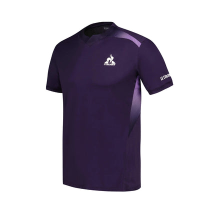 Introducing the Le Coq Sportif Pro Men's Badminton T-Shirt in Deep Purple. This short-sleeved athletic shirt features a V-neck design and is made from breathable polyester, ensuring comfort during play. The brand's logo is prominently displayed in white on the upper left chest, while "Le Coq Sportif" adorns the right sleeve. Subtle textured lines across the shoulders enhance fluidity of movement.