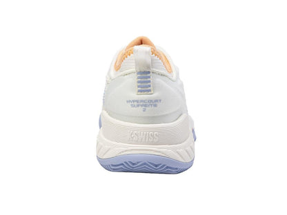 The image displays the rear view of a K-Swiss Hypercourt Supreme 2 HB women's badminton shoe in star white, complemented by light blue and beige accents. The shoe features the "Hypercourt Supreme 2" text on the heel, a textured sole for improved grip, and enhanced durability with Durawrap X technology.