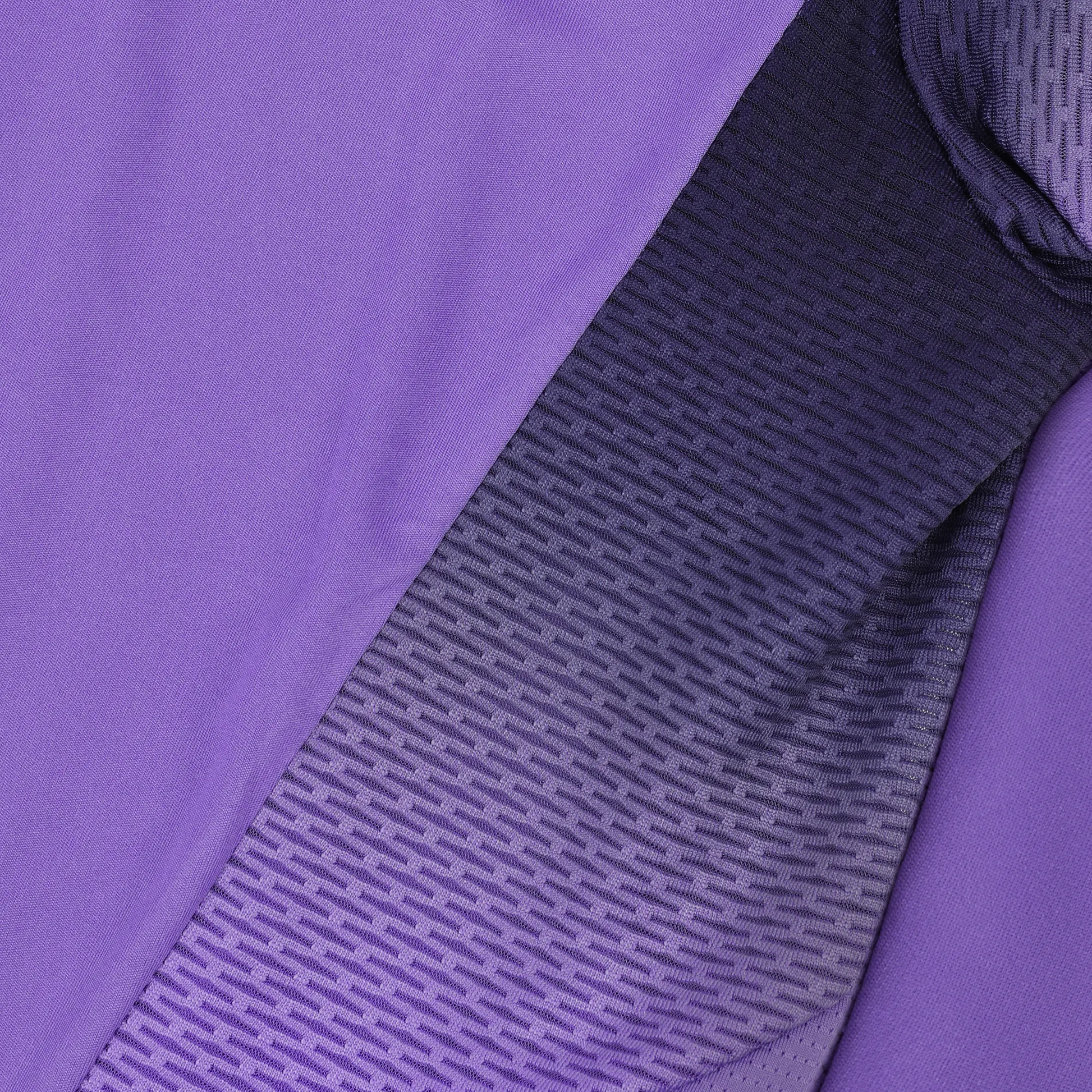 A close-up of a textured fabric featuring a gradient from purple to dark purple evokes the design of the Le Coq Sportif Pro Mens Badminton T-Shirt in Chive Blossom by Le Coq Sportif. The pattern of small, horizontal lines on breathable polyester materials enhances fluidity in movement, creating an appealing transition of colors and textures.