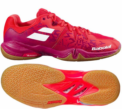 Cherry Tomato Babolat Shadow Spirit men's badminton shoes, highlighting a red and pink color scheme with a white logo. The sides boast an intricate design, and the gum Michelin rubber soles are equipped with patterned treads for enhanced grip traction.