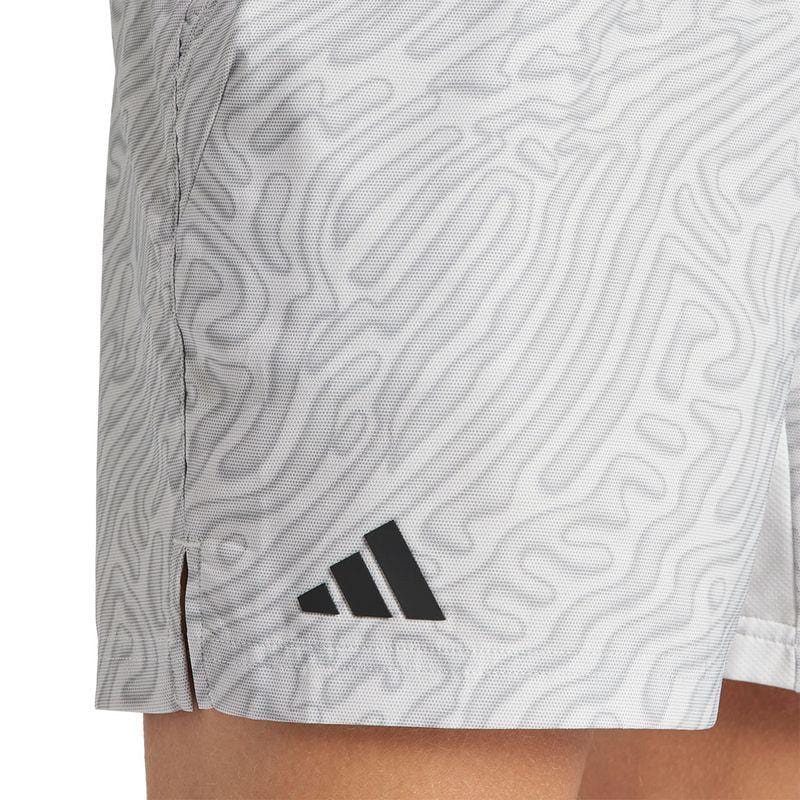 A close-up depicts someone wearing the ADIDAS Melbourne Men's Pro 7 Inch Badminton Shorts in grey, showcasing a textured wave pattern. Made from recycled polyester, these shorts incorporate HEAT.RDY technology and are adorned with a small black logo featuring three diagonal bars near the hem.