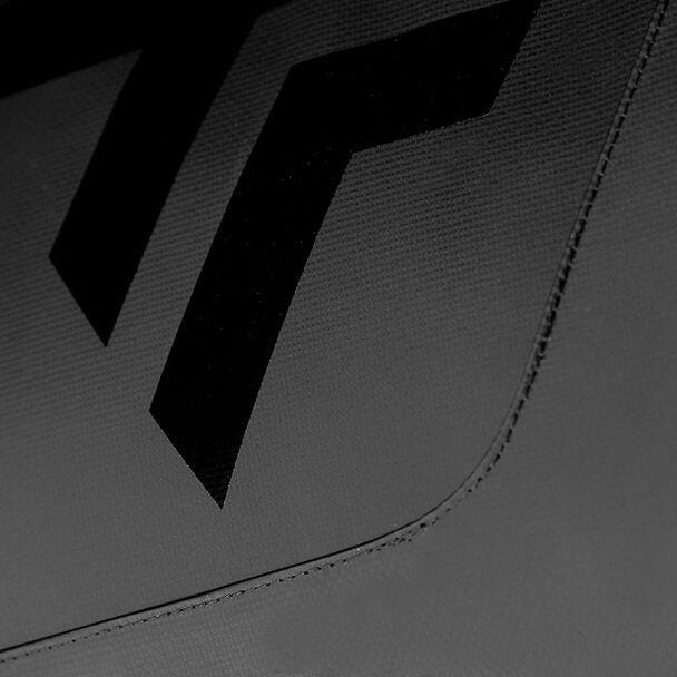 A close-up image showcases a textured tarpaulin fabric surface with black geometric shapes and two prominent chevron-like designs against a gray background, echoing the sharp contrast of the Tecnifibre Tour Endurance 2024 12 Racket Badminton Bag in Ultra Black by Tecnifibre.