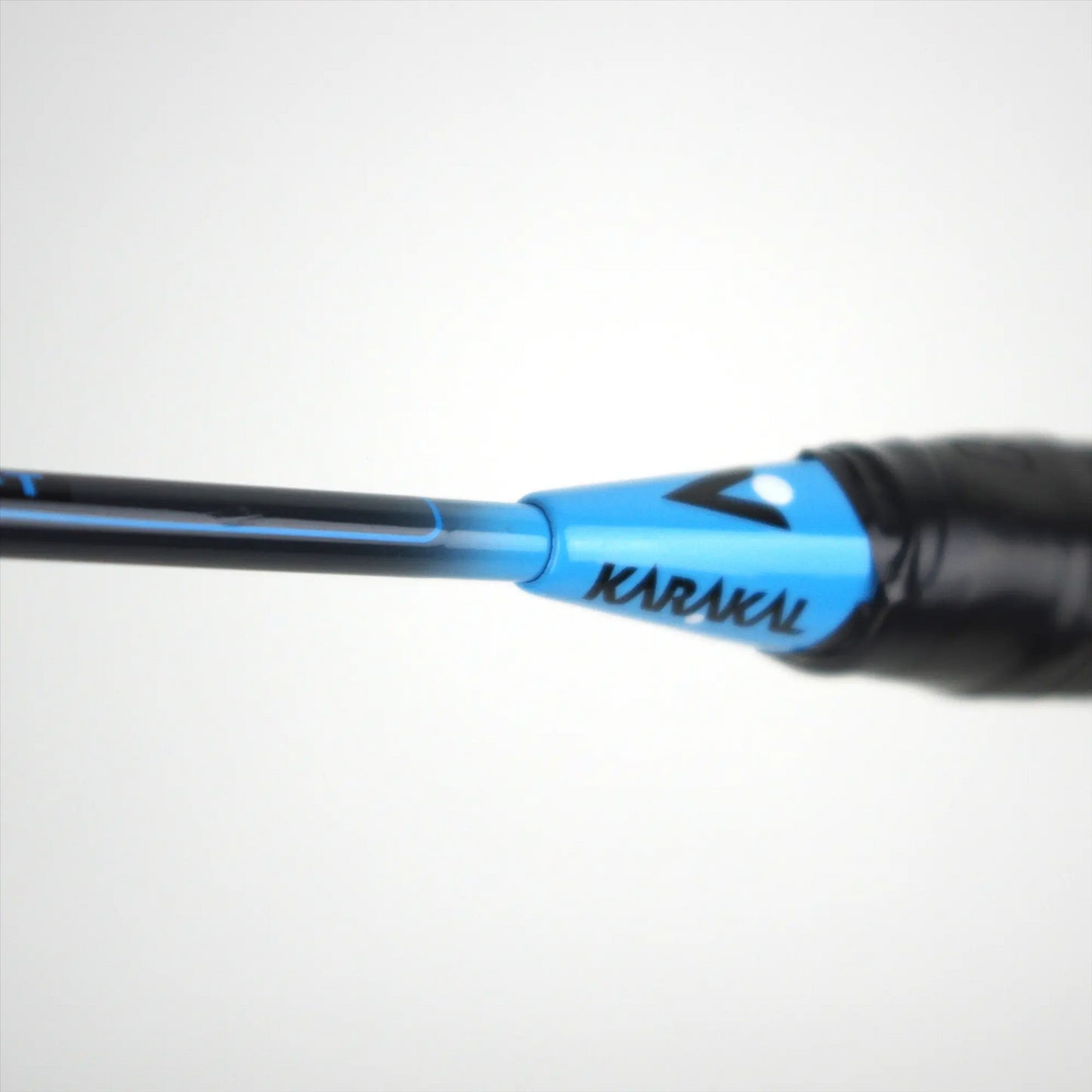 Close-up of a black and blue Karakal CB-3 2.1 Badminton Racket handle against a plain white background, ideal for beginner players seeking quality gear.