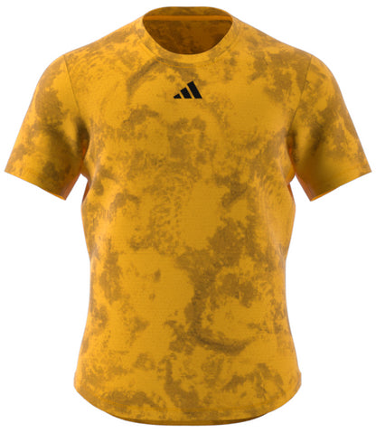 A short-sleeved athletic shirt with a yellow and ochre marbled pattern, showcasing a small black triangular logo on the chest. This design is influenced by the adidas Paris Men's Freelift Badminton T-Shirt - Gold / Yellow collection, providing exceptional performance with HEAT.RDY technology.