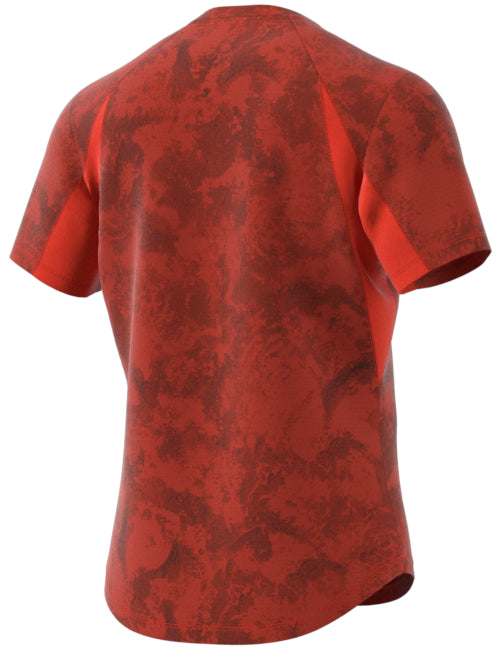 The ADIDAS Paris Men's Freelift Badminton T-Shirt, offered by adidas, showcases a stylish red short-sleeve design with a darker red abstract pattern and textured appearance that perfectly blends fashion with function. Equipped with HEAT.RDY technology, this shirt ensures you remain cool and comfortable. It is displayed against a plain white background.