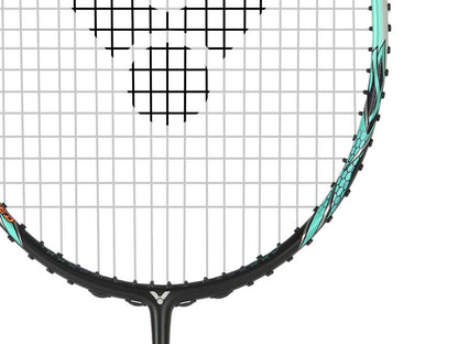 Close-up of a Victor Auraspeed 90K Metallic 4U badminton racket by Victor, featuring a black grid pattern. The frame is primarily green, accented with intricate black and orange designs along the sides for excellent shock absorption. The background is plain white.