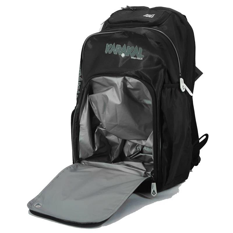 The Karakal Pro Tour 30 2.1 Badminton Backpack in Black/White features a partially open front compartment showcasing a grey interior. Equipped with padded shoulder straps, a wet/dry compartment, and numerous pockets and zippers, it is ideal for both sports and travel.