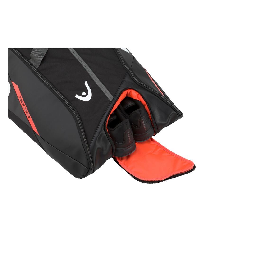 A stylish black badminton bag with orange accents, similar to the HEAD Tour Team 12R Monstercombi design, is shown in partial view. The open compartment reveals a pair of black sneakers inside. The white background accentuates its sleek appearance.