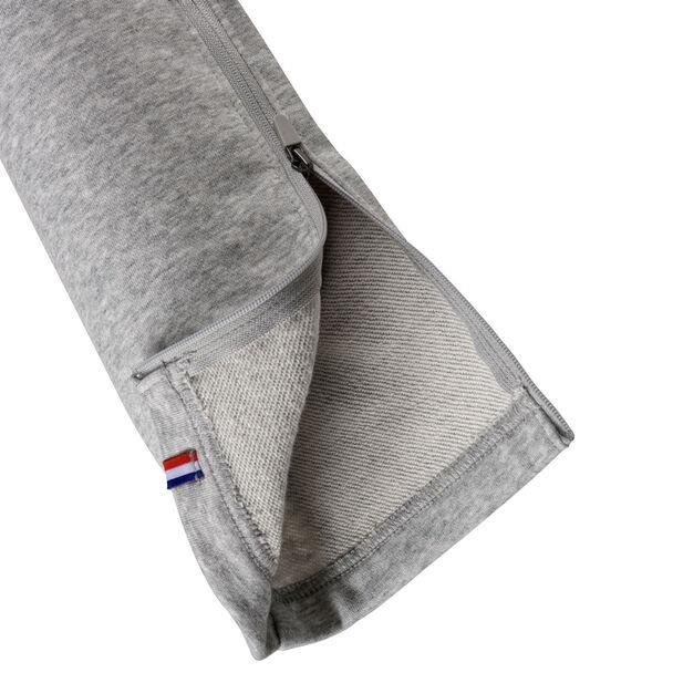 Close-up of the Tecnifibre Unisex Team Badminton Pants in silver, showcasing a sleek design with a partially opened zipper and visible interior lining. A small tag featuring a red, white, and blue striped pattern is attached to the edge.