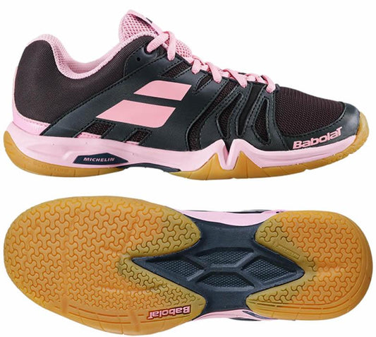 The Babolat Shadow Team Women's Badminton Shoes in Black/Peony boast a sleek black design accented by peony highlights, making them an excellent choice for indoor courts. The brown gripsole is enhanced with pink details and features a textured pattern designed for optimal traction on badminton courts.