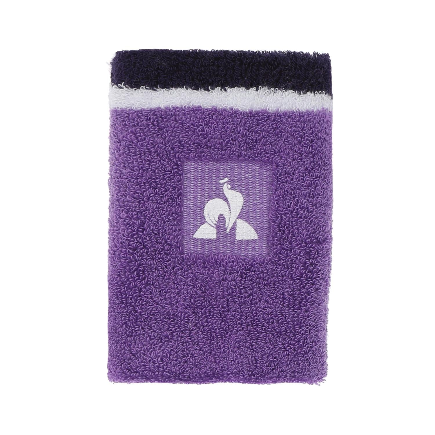 A rectangular, purple towel featuring a decorative band with a white logo of a stylized bird against a striped background closely resembles the design elements found on the Le Coq Sportif Badminton Sweatband - Chive Blossom. The towel's edges are adorned with black and white stripes.