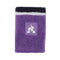 A rectangular, purple towel featuring a decorative band with a white logo of a stylized bird against a striped background closely resembles the design elements found on the Le Coq Sportif Badminton Sweatband - Chive Blossom. The towel's edges are adorned with black and white stripes.