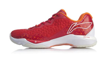 Introducing the Li-Ning Dagger II SE Men's Badminton Shoe in red, which showcases a stylish white logo on the side along with a textured pattern and orange accents. Designed for optimal athletic performance, it features TUFF-TIP Technology. The shoe includes a white and red sole tailored for sports activities, complemented by a low-cut silhouette and lace-up closure.