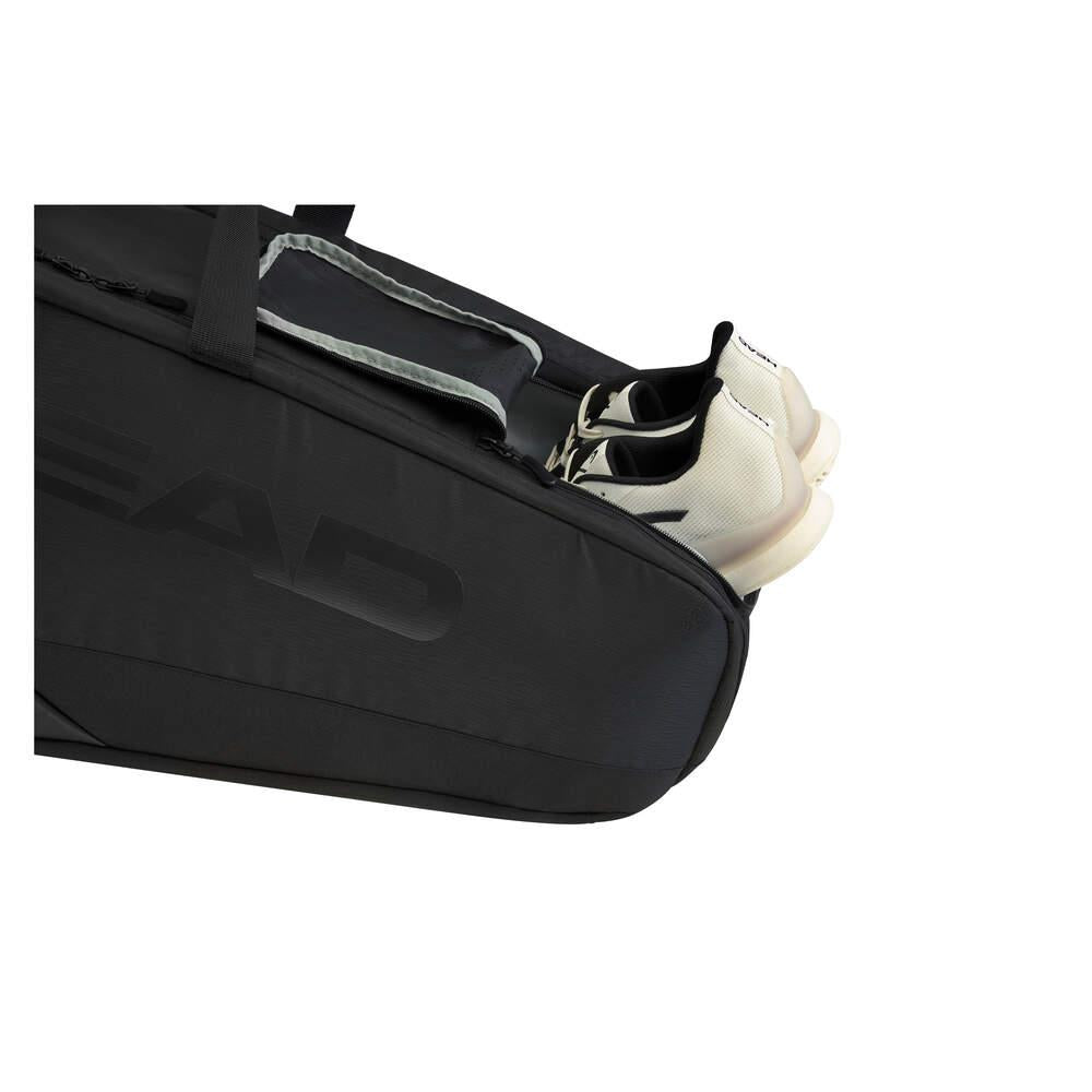 A black sports bag with a partially open compartment reveals a pair of white shoes nestled inside, reminiscent of the sleek HEAD Pro X Legend 9 Badminton Racket Bag L by HEAD.