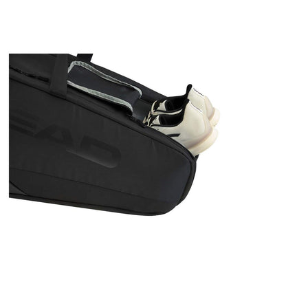 A black sports bag with a partially open compartment reveals a pair of white shoes nestled inside, reminiscent of the sleek HEAD Pro X Legend 9 Badminton Racket Bag L by HEAD.