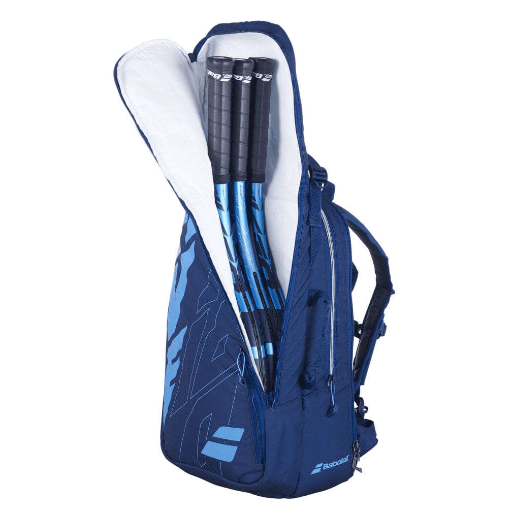 A partially open blue Babolat Pure Drive Backpack reveals three blue and black tennis rackets inside. The backpack, featuring comfortable shoulder straps and a side pocket, proudly displays the Babolat logo on the side. It's an ideal choice for carrying your badminton essentials.