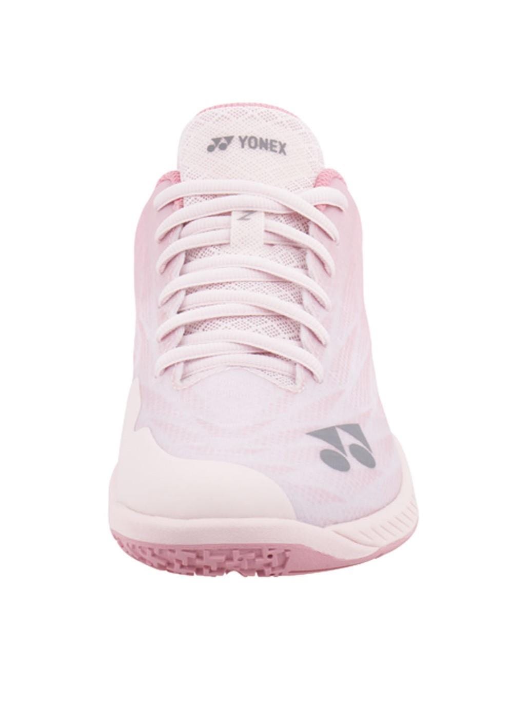 The Yonex Power Cushion Aerus Z2 Women's Badminton Shoes in light pink feature a front view highlighting the Power Cushion technology. The design includes white laces and a textured pink sole, complete with the Yonex logo on both the tongue and side for an optimal performance-inspired look.