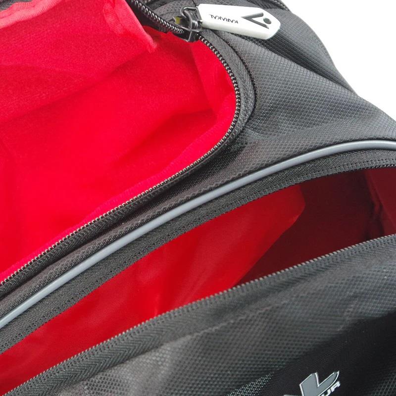 Close-up of a Karakal Pro Tour 30 2.1 Badminton Backpack in black and white, showcasing the red lining and an open zipper pocket. The visible inner compartment provides ample space along with a wet/dry compartment. The bag features the Karakal logo on its durable fabric exterior and is equipped with padded shoulder straps for added comfort.