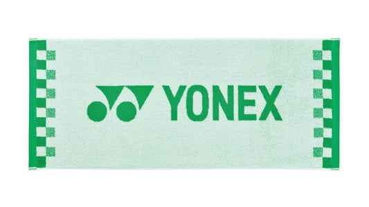 The Yonex AC1109EX Face Towel in white, made from premium cotton, showcases a checkered pattern on the sides. The Yonex logo and name are prominently displayed in dark green across the center, offering both performance and style as an ideal workout towel.