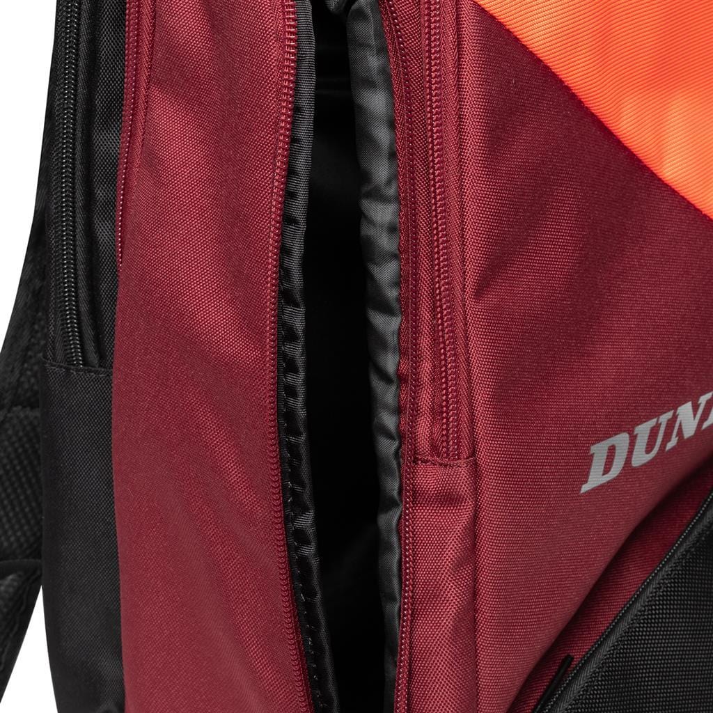 A close-up of the Dunlop CX Performance Badminton Backpack in black and red shows a partially open zipper, providing a sneak peek of the interior. The brand name "DUNLOP" is partially visible on the fabric, alluding to its CX Performance line, ideal for securely carrying your rackets.