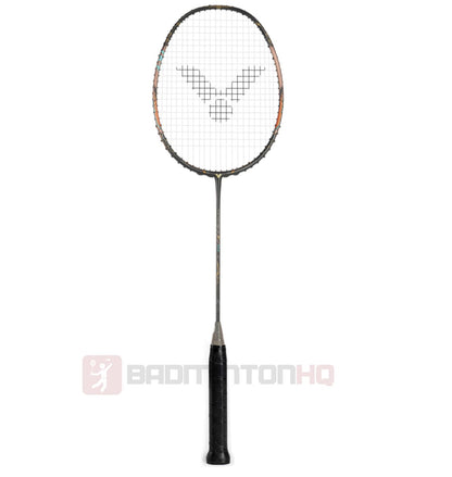 The Victor Thruster F Ultra Badminton Racket - Moonless Night by Victor boasts a black handle and an orange and black frame, presented vertically. Its strings are tightly woven, showcasing a logo pattern at the center, ideal for executing fast, controlled attacks. A logo and "BADMINTONHQ" can be seen at the bottom.