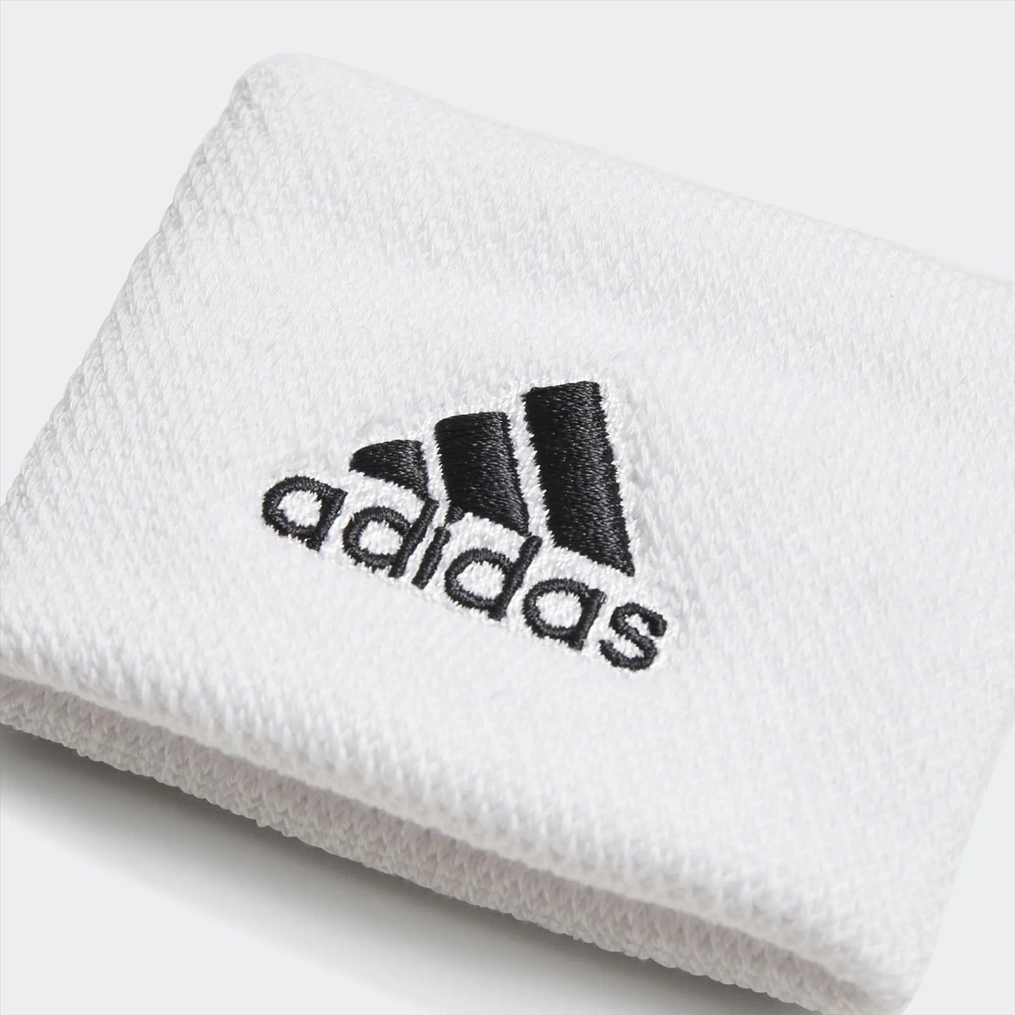 The adidas Wristband Sweatband Small - White features a design that highlights its soft, moisture-absorbing material, complete with a white color and the logo alongside the iconic three stripes in black.