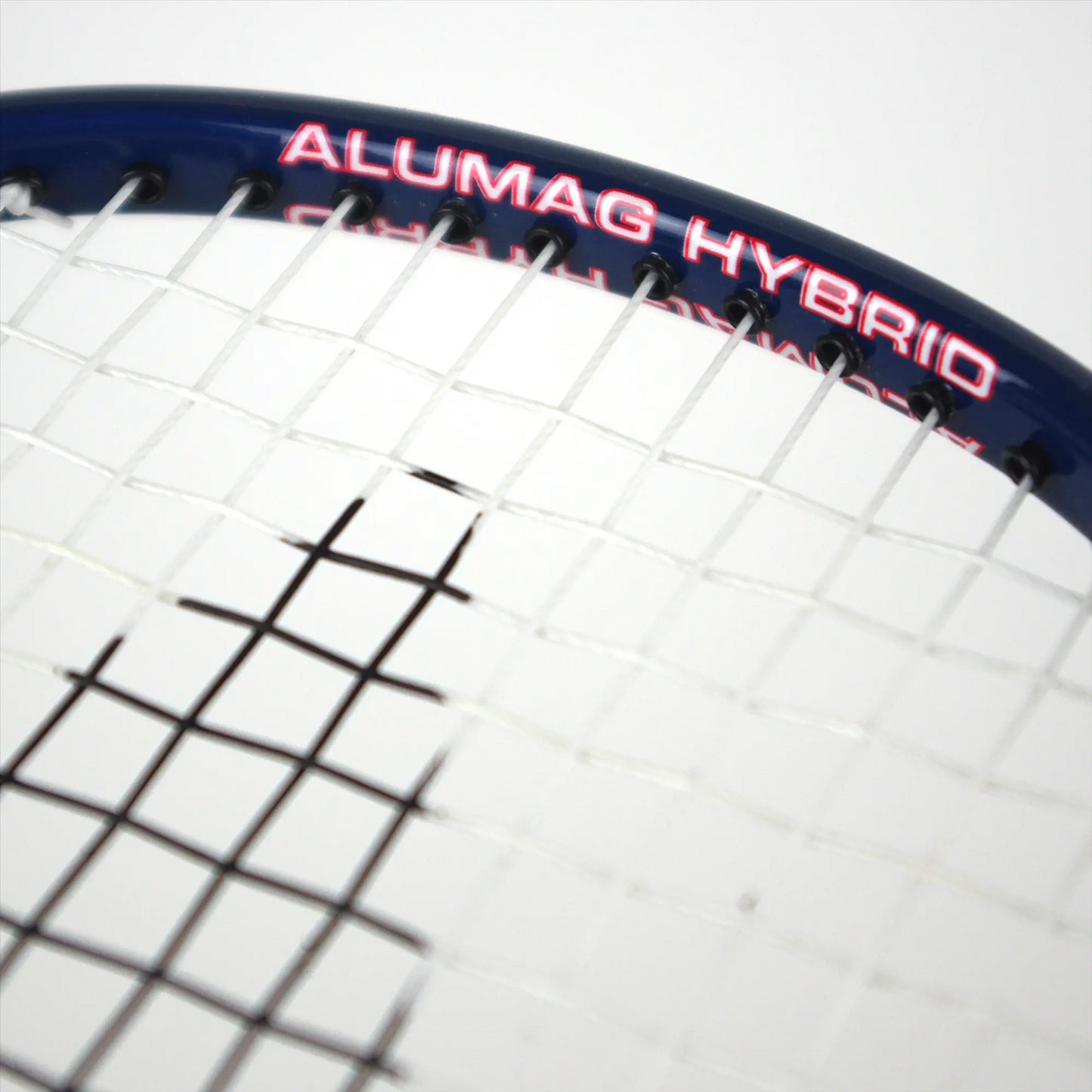 Close-up of a badminton racket highlighting its intricate string pattern and dark blue upper frame. The phrase "Karakal" stands out in bold red lettering on this graphite marvel, reminiscent of an isometric head design from the Karakal CB-7 2.1 series.