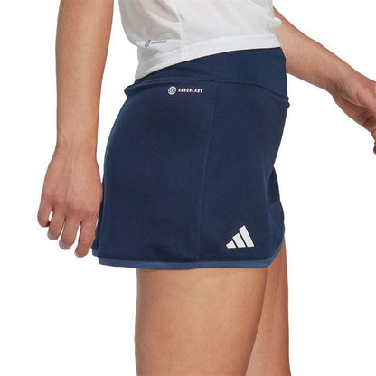 A person wearing an adidas Women's Club Badminton Skirt in navy, which includes built-in short tights for added comfort.