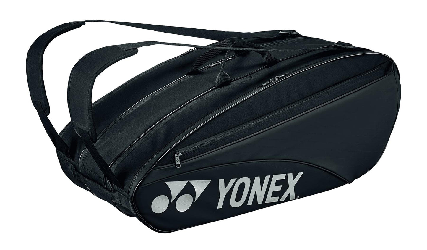 The Yonex 42329EX Team 9 Racket Badminton Bag in black boasts a sleek, elongated design with multiple compartments, including a dedicated shoe section. It accommodates up to 9 rackets and features two shoulder straps for easy carrying. The side prominently displays the white Yonex logo.