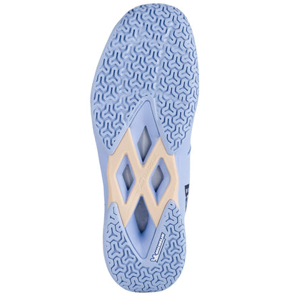 The image highlights the sole of a Babolat Shadow Team 2 Women's Badminton Shoe in a light blue colorway, displaying an intricate tread pattern made up of small, curved shapes with a diamond-shaped cutout at the center crafted from durable Michelin rubber. The brand logos are prominently visible on the sole.