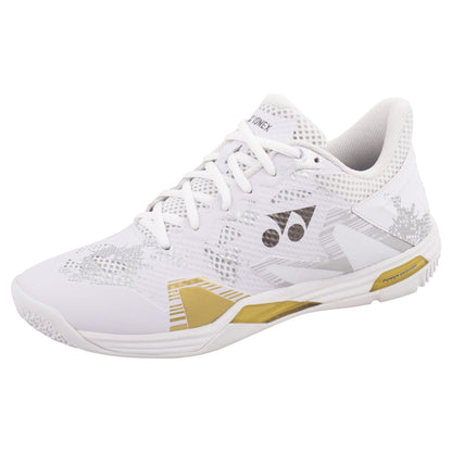 Introducing the Yonex Power Cushion Eclipsion Z3 Men's Badminton Shoes in White and Gold. These athletic shoes feature a gold and silver geometric design with a white lacing system, textured sole, and mesh upper material. Enhanced with Yonex's signature Power Cushion technology for superior comfort, these stability shoes prominently display the Yonex brand logo on the side.