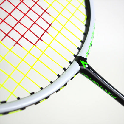 Close-up of a Karakal BZ 20 2.1 Badminton Racket, highlighting its isometric head with red and yellow strings against a predominantly black frame with a high-performance PU Super Grip. Green text on the frame reads "DESIGNED IN THE UK.