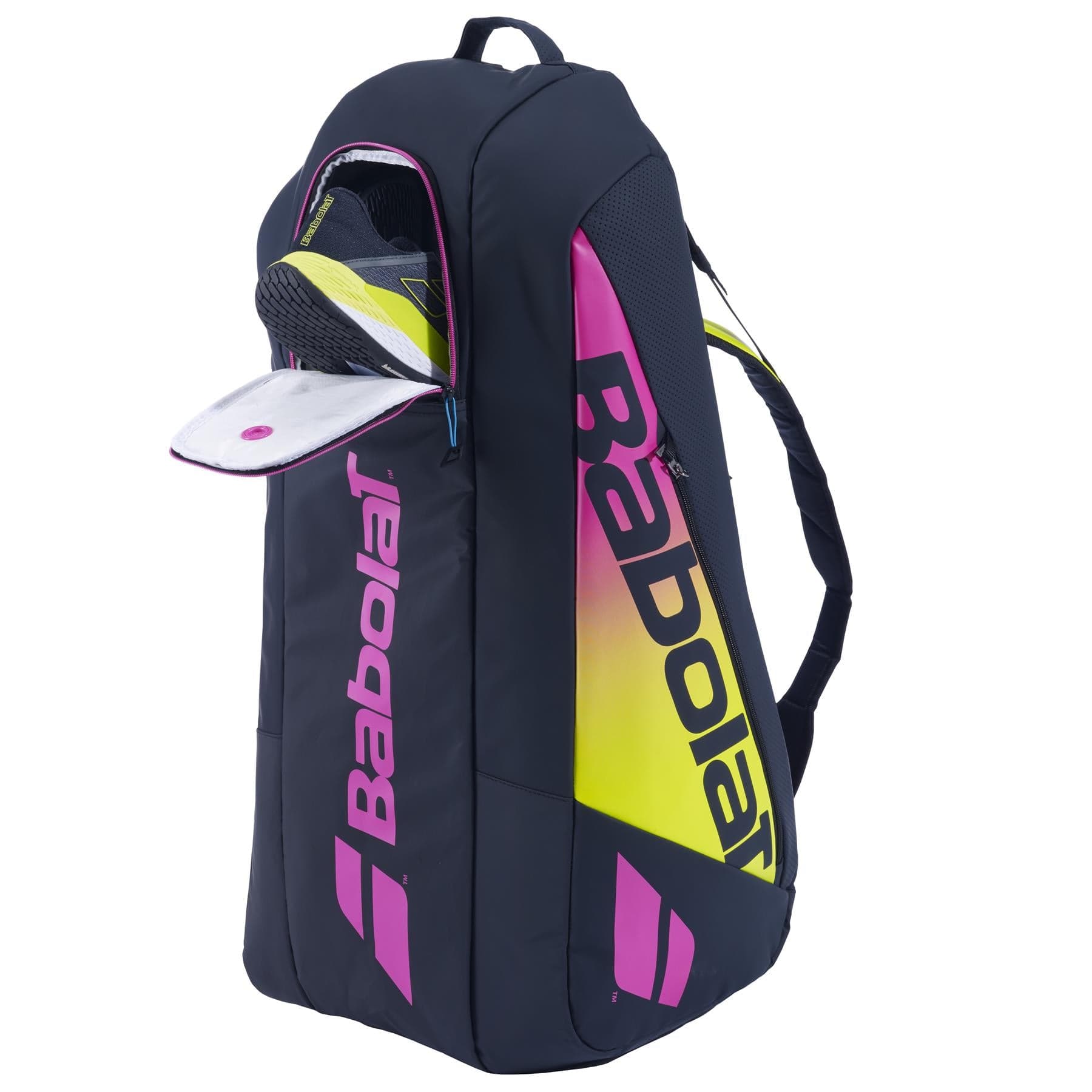 The Babolat RH6 Pure Aero Rafa II Badminton Bag in blue, yellow, and pink stands upright with its top compartment open. Featuring shoulder straps and a handle, it's expertly designed for carrying tennis or badminton gear.