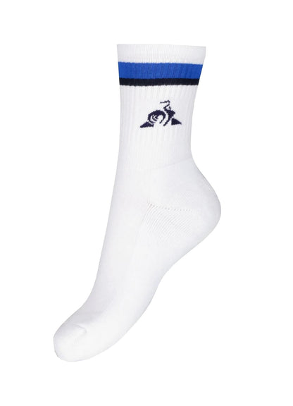 The Le Coq Sportif Sports Socks in Lapis Blue feature a white base with a blue and black stripe at the top and a small navy blue rooster logo above a triangle. Designed for maximum comfort and breathability, these socks are showcased upright against a plain background.