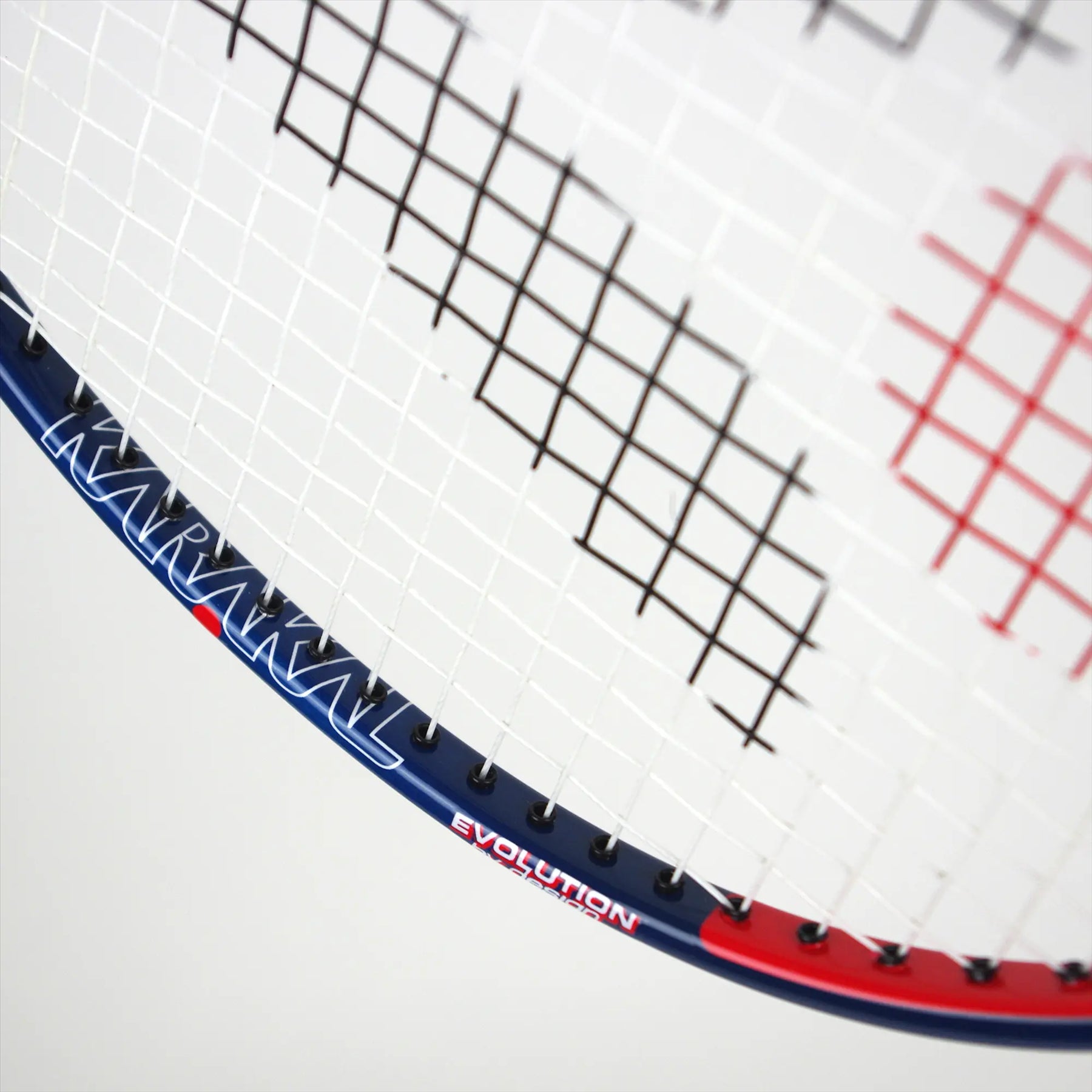 Close-up of a badminton racket's strings and frame. The graphite frame is blue and red with the words "KARAKAL" and "CB-7 2.1" printed on it, showcasing an isometric head design.