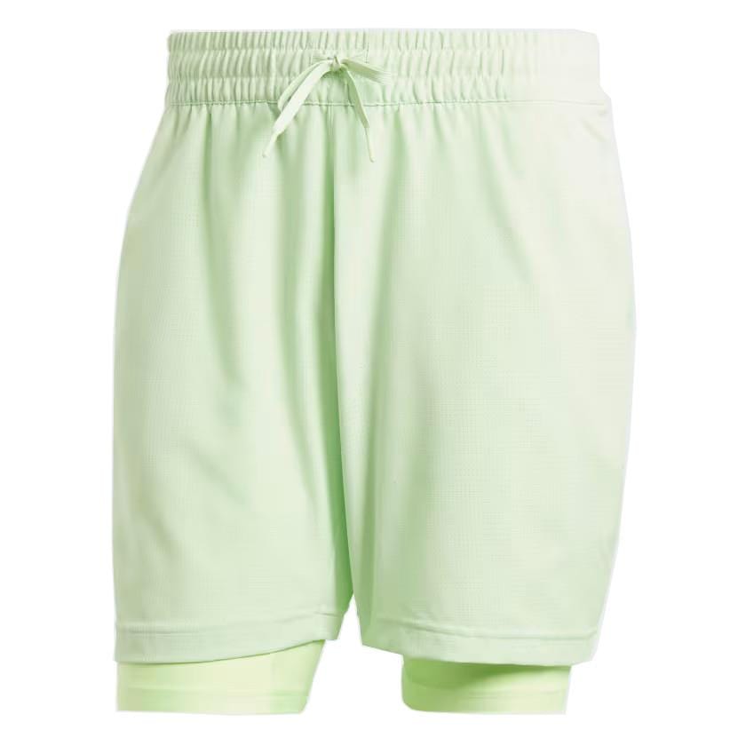 The ADIDAS Melbourne Men's 2in1 Badminton Shorts in green, crafted by adidas using recycled materials, feature an elastic waistband with a drawstring. The inner layer extends slightly below the outer layer for enhanced comfort, making their lightweight design ideal for sports or casual wear.