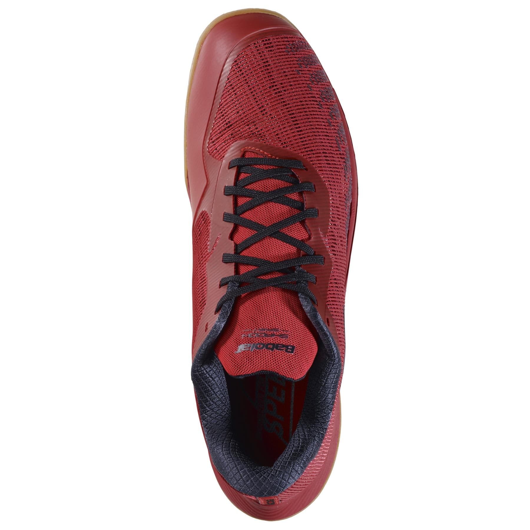 Top view of the Babolat Shadow Spirit 2 Men's Badminton Shoes in a lightweight poppy red color, ideal for badminton. These shoes feature black laces and a black collar, with a comfortable design that includes a textured pattern on the surface and a gum-colored sole.