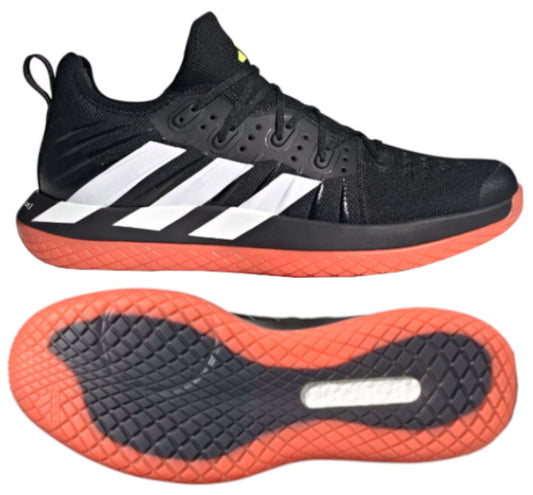 The adidas Stabil Next Gen Primeblue men's indoor court badminton shoes in core black with red accents feature white stripes and vibrant orange BOOST soles. The upper includes lace-up fastenings, while the sole is designed with a textured grip pattern. Displayed from both side view and bottom view, these shoes are crafted for peak performance on indoor courts.