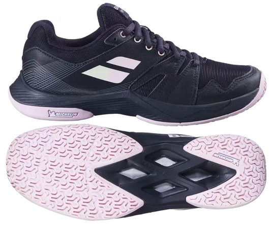 The Babolat Shadow Team 2 Women’s Badminton Shoes in Black feature side and sole views, a textured Michelin-branded outsole for grip, and white Babolat logo stripes on the side for a sporty touch.