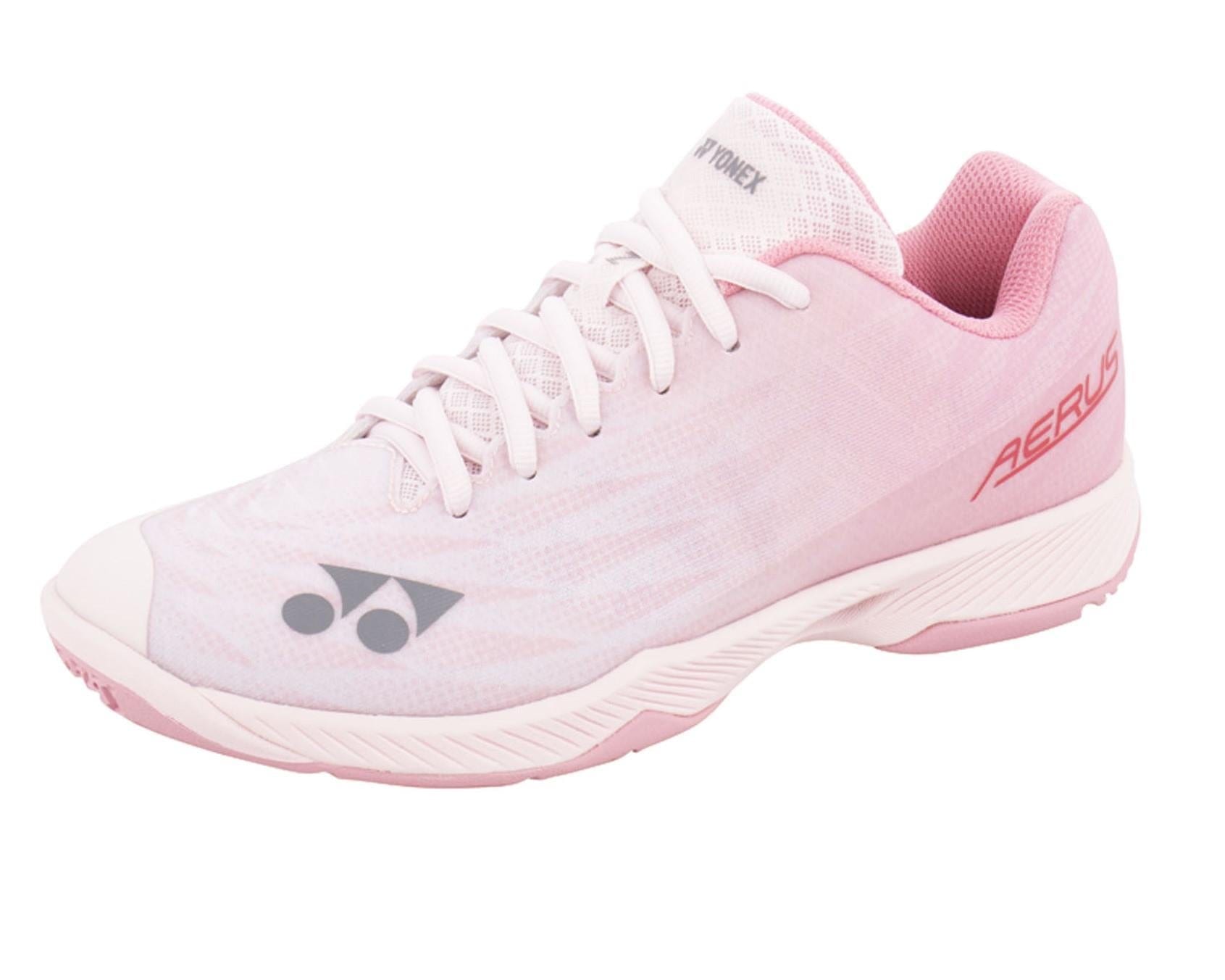 The Yonex Power Cushion Aerus Z2 Women's Badminton Shoes in Light Pink showcase a laced design. They feature the brand logo near the toe and "AERUS" by the heel, along with a textured sole for superior grip on the court.