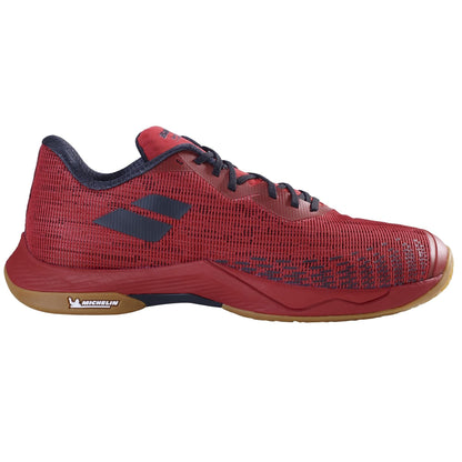 Introducing the Babolat Shadow Spirit 2 Men's Badminton Shoe in Black and Poppy Red. This shoe features a textured upper design with striking red accents, ensuring it stands out on the court. Its lightweight construction promises comfort, while the light brown sole is imprinted with "Michelin." The signature logo is elegantly placed on the side for a stylish finish.