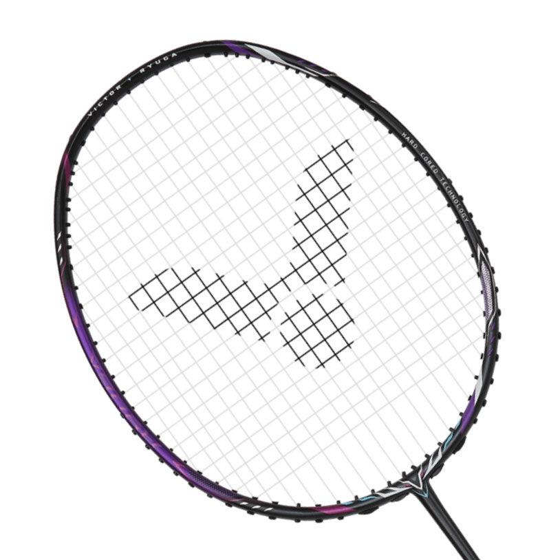 A close-up shot of the Victor Thruster Ryuga II 3U badminton racket head reveals a grid of white strings and a central black, V-shaped logo. The frame is primarily black with stylish purple accents, featuring decorative elements suitable for offensive players. The image is set against a white background.