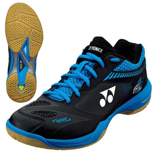 A pair of Yonex Power Cushion 65Z2 Men Badminton Shoes in Black Blue, featuring a gum sole. One shoe is displayed upright highlighting the Yonex branding, while the other showcases its hexagonal tread pattern. The design includes blue accents on the laces and mesh panels, making it perfect for professional players who desire both performance and style.