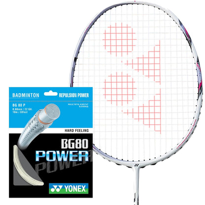 A badminton racket with a red pattern on the strings is positioned beside a packet of Yonex BG 80 Power Badminton String in white, known for offering high repulsion power and a hard feeling. The packaging is black and blue, featuring a silver shuttlecock graphic.