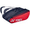 The Yonex 423212EX 12 Piece Racket Bag in scarlet features a stylish black and red design with plenty of storage space and a comfortable shoulder strap, prominently showcasing the classic white Yonex logo.